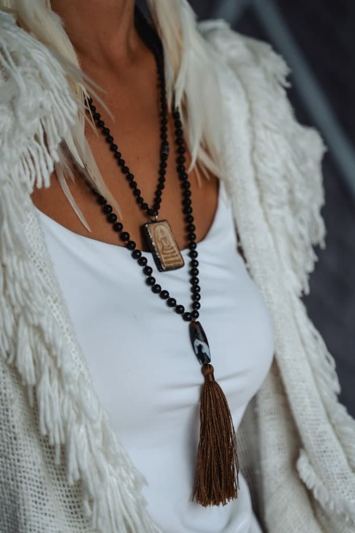 Close detail of a beaded mala necklace over a white top