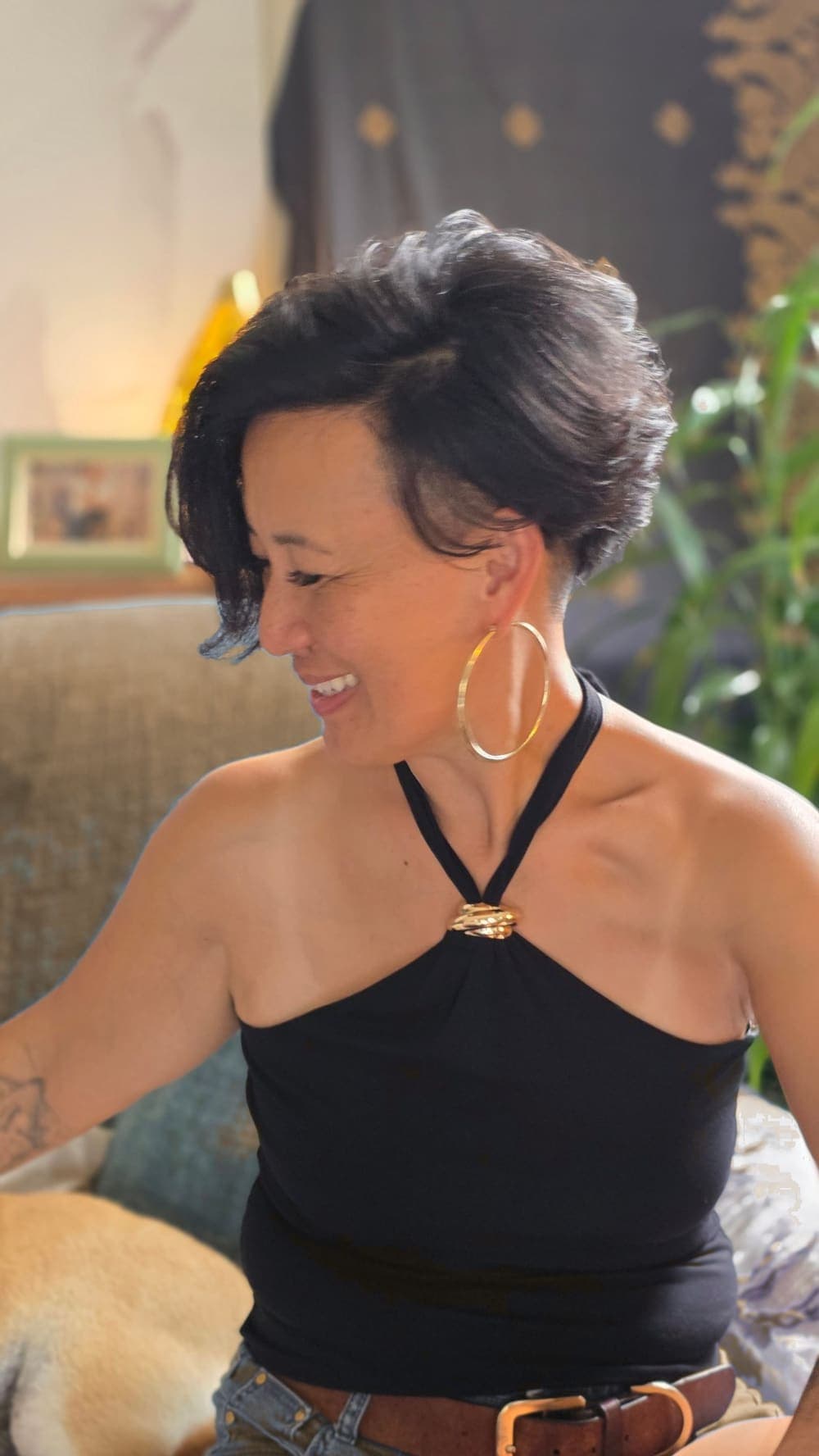 Oomee laughing and looking away, warm light, gold hoop earrings